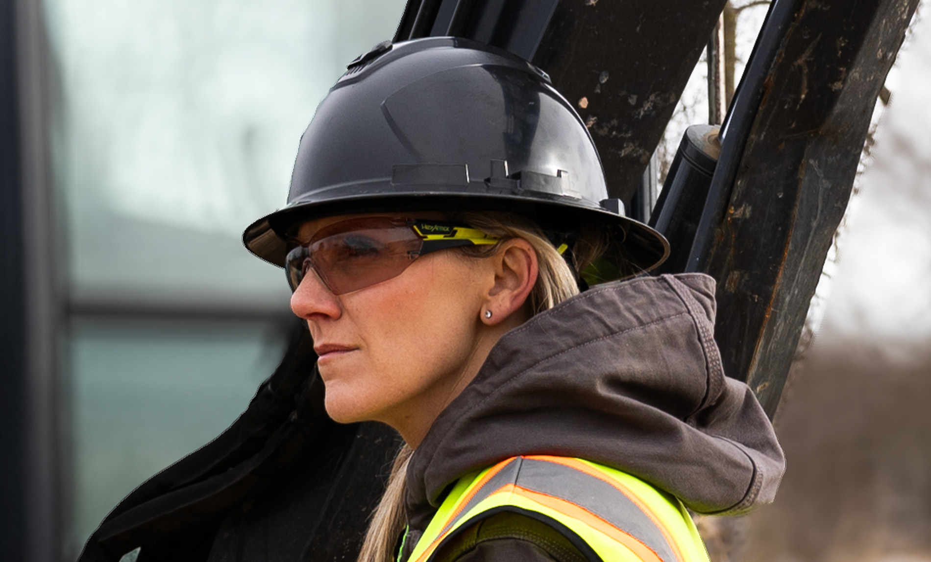 Women construction worker on worksite wearing MX225 safety glasses with CBR23 blue light blocking safety tint.